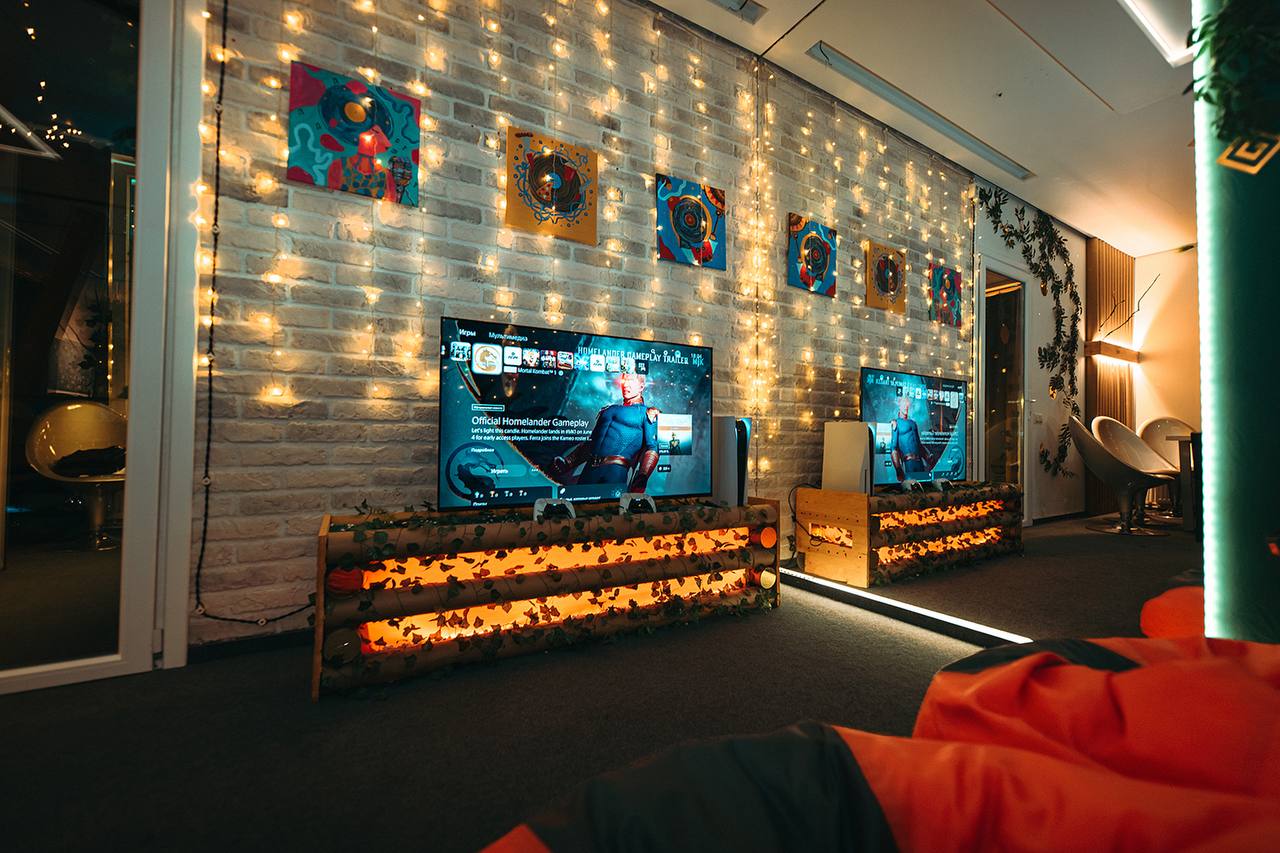 Игровая зона с PlayStation 5 и большими телевизорами у кирпичной стены